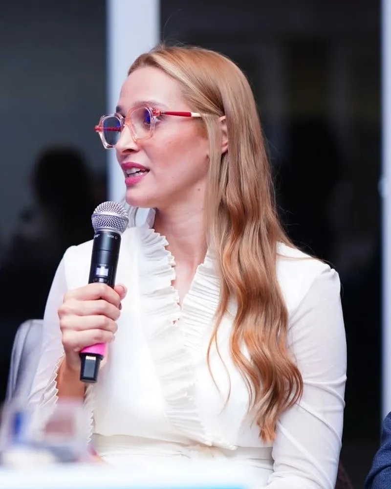 Advogada Natalia Saar com microfone, falando em um painel